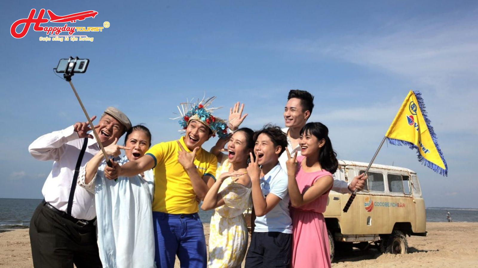 Nhóm khách du lịch gia đình vui vẻ chụp ảnh selfie cùng hướng dẫn viên cầm cờ tại bãi biển