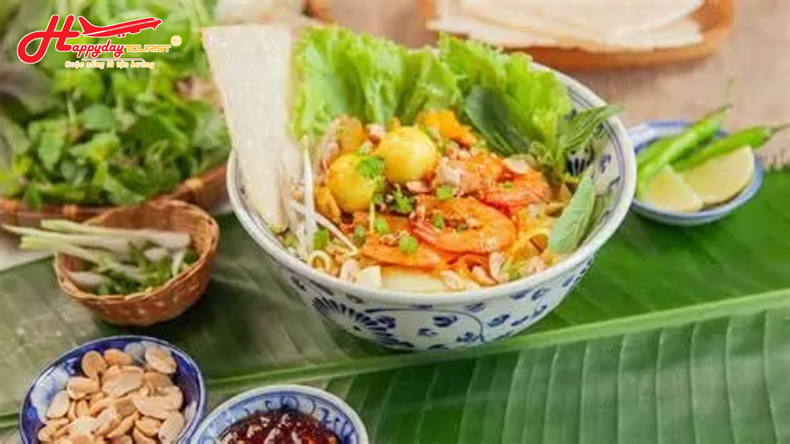 Tô mì Quảng tôm thịt ăn kèm rau sống và bánh tráng đặt trên lá chuối xanh