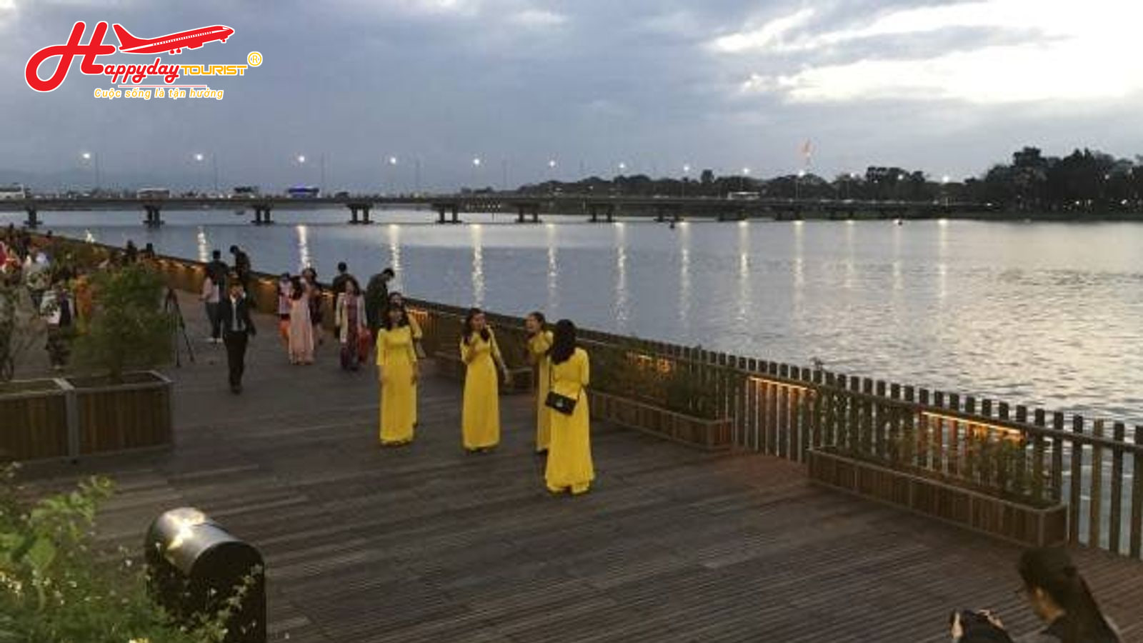 Tuyến phố đi bộ lát gỗ ven sông Hương với mọi người đang dạo mát và chụp ảnh