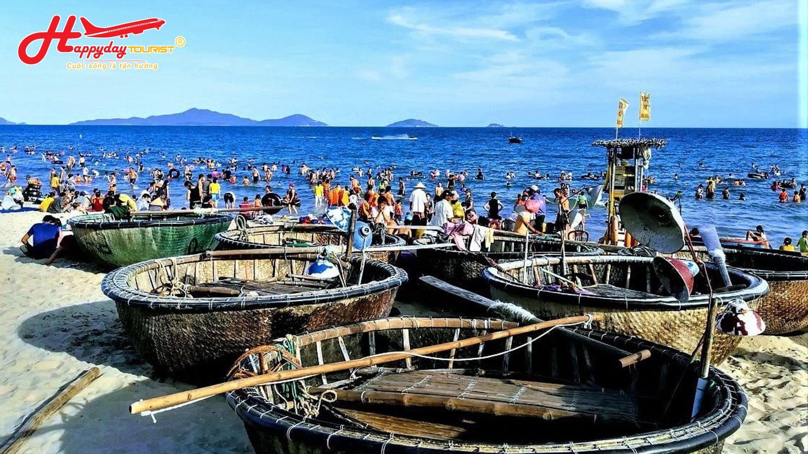 Nhiều thuyền thúng nằm trên bãi cát biển An Bàng với khung cảnh người dân tắm biển tấp nập phía xa ở Rừng dừa Bảy Mẫu